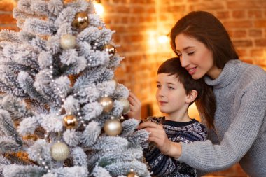 Anne ve oğlu evde Noel ağacı süslüyorlar. Birlikte zaman geçirmek, ilişkiler ve insanlar konsepti. Kış tatilleri, Noel kutlamaları, yeni yıl konsepti.