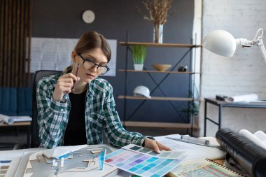 Renk paletinde çalışan kadın iç mimar. Renk örnekleri kullanarak, proje için yeni fikirler arayarak inşa etmek için renkleri seçin. İş yerinde güzel bir kadının portresi.