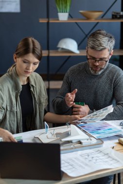 İç mimar takımı renk paletiyle ofiste çalışıyor. Mimarlar bina renklerini renk örnekleri, çizim ve inşaat projeleri kullanarak seçerler. İş yerinde tartışan ortaklar