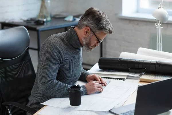 Diseñador de interiores que trabaja en la oficina con planos. Ingeniero inspeccionar plan arquitectónico, bosquejando un proyecto de construcción. Retrato de hombre barbudo guapo en el lugar de trabajo. Concepto de construcción empresarial — Foto de Stock