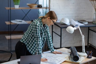 Ofiste planlarla çalışan iç mimar. Mühendis mimari planı inceliyor, bir inşaat projesi çiziyor. İş yerinde güzel bir kadının portresi. İş inşa kavramı