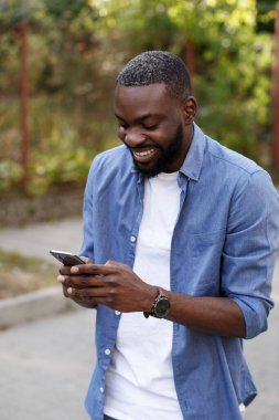 Mutlu adam cep telefonu uygulamaları kullanıyor, mesaj atıyor, internette geziniyor, akıllı telefona bakıyor. Akıllı telefon kullanıp gülümseyen yakışıklı bir Afro-Amerikalı. Mobil aygıtlarla çalışan gençler