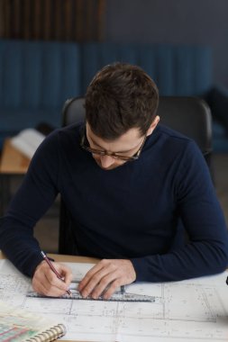 Ofiste planlarla çalışan bir mimar. Mühendis mimari planı inceliyor, bir inşaat projesi çiziyor. İş yerinde oturan sakallı yakışıklı bir adamın portresi. İş inşa kavramı