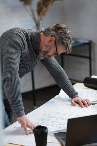 Arquitecto trabajando en la oficina con planos. Ingeniero inspeccionar plan arquitectónico, bosquejando un proyecto de construcción. Retrato de hombre barbudo guapo sentado en el lugar de trabajo. Concepto de construcción empresarial — Foto de Stock