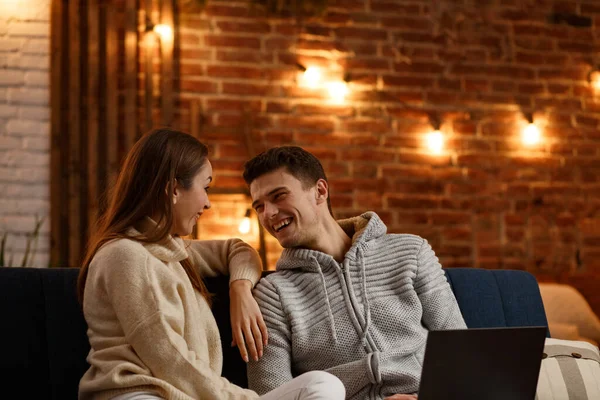 Vacaciones de invierno, celebraciones de Navidad, concepto de Año Nuevo. Retrato de una hermosa pareja sonriente viendo películas navideñas en casa. Hermosa pareja joven en casa disfrutando pasar tiempo juntos — Foto de Stock