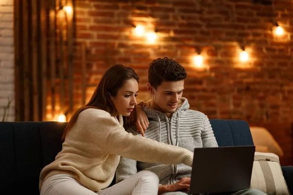 Vacaciones de invierno, celebraciones de Navidad, concepto de Año Nuevo. Retrato de una hermosa pareja sonriente viendo películas navideñas en casa. Hermosa pareja joven en casa disfrutando pasar tiempo juntos — Foto de Stock