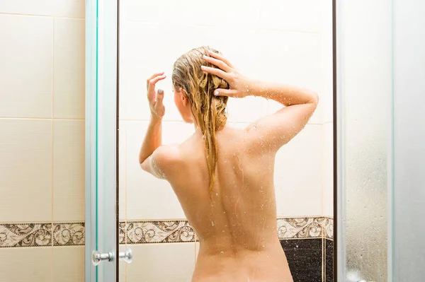 Young fit woman in shower washing her perfect fit body