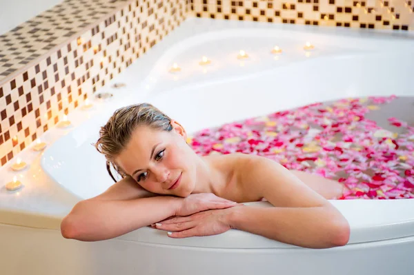バラの花びらのお風呂でリラックスできる魅力的な女の子 — ストック写真