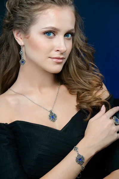 luxury jewelry and fashion concept. A model demonstrate jewelry collection - bracelet earrings necklace and ring on dark blue background