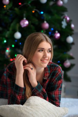 Evde yatakta mutlu güzel kız portresi ile süslenmiş Noel ağacı arka planda