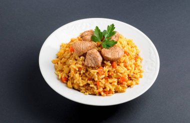 Beyaz bir tabak etli pilav. Gri zemin üzerine pilav