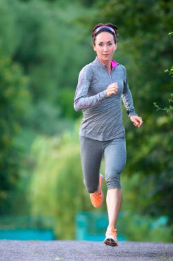 Kadın atlet şehir parkında yaklaşan çalışır. Açık havada çalışan kadın