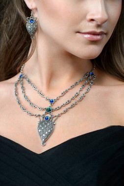 Takı ile zarif şık kadın. Güzellik genç modeli ile karanlık bir arka plan üzerinde gümüş kolye.