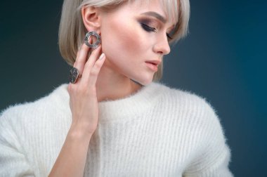 Güzel bir yüzük ve küpeler Studio mavi bir arka plan üzerinde poz ile güzel bir sarışın kadın portresi