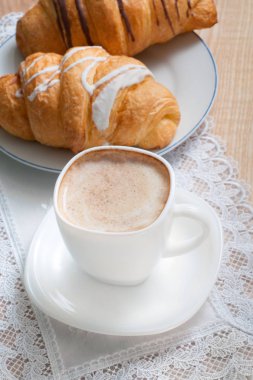 Kapuçino kruvasan ile. Kahve süt ve iki croi