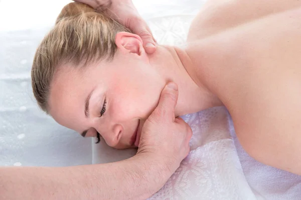 Las manos de los hombres hacen un masaje terapéutico del cuello para una chica acostada en — Foto de Stock