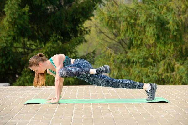 Jeune femme sportive en survêtement faisant de l'exercice de planche lors d'un — Photo