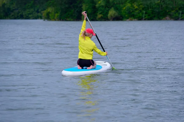 Widok z tyłu dziewczyny z niebieskimi włosami siedzi na pokładzie paddle na Rive — Zdjęcie stockowe