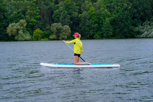 Jeune fille pagayant à bord d'un SUP sur un lac calme en ville. Sup sur — Photo