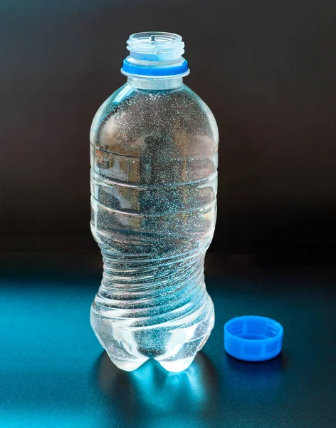opened bottle of water on blue background
