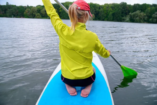 Vue arrière d'une fille sportive avec les cheveux blancs assis sur une planche wi — Photo