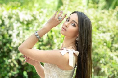 Güzel kız, bahar doğasında izole edilmiş mücevherler gösteriyor.