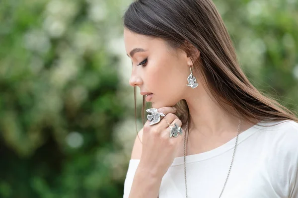 Beautiful woman in a necklace, earrings and a ring. Model in silver jewelry.