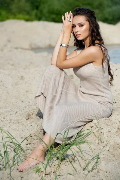 young  woman with stylish silver jewelry sitting on the sand