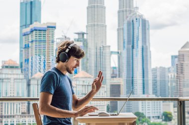 Genç adam bir yabancı dil öğreten ya da büyük bir şehir zemin karşı balkonunda internette yabancı dil öğrenir. Online dil okulu yaşam tarzı