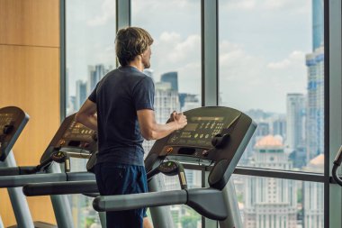 Bir spor salonunda büyük bir şehir çerçevede bir koşu bandı üzerinde çalışan adam. egzersiz, fitness ve sağlıklı yaşam konsepti.