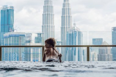 Mavi gökyüzünde şehir manzaralı açık yüzme havuzunda çocuk