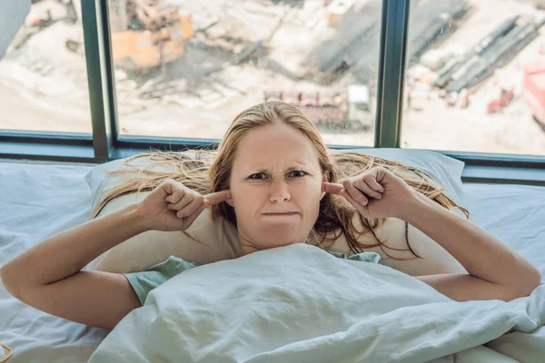 Νεαρή Γυναίκα Ξαπλωμένη Στο Κρεβάτι Καλυμμένα Αυτιά Λόγω Θορύβου Κατασκευή — Φωτογραφία Αρχείου