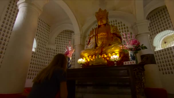 O femeie se roagă la o statuie de aur a lui Buddha din interiorul templului Kek Lok Si de pe insula Penang, Malaezia — Videoclip de stoc