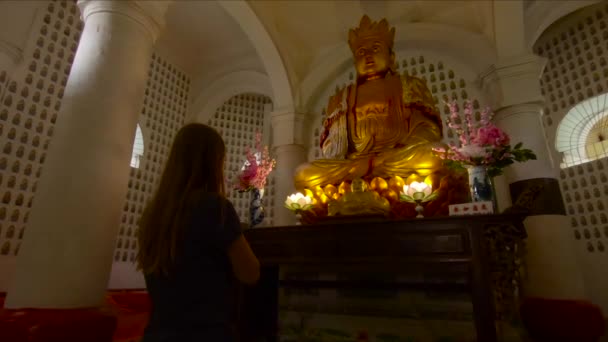 Vrouw bidden tot een gouden Boeddhabeeld binnenkant van de Kek Lok Si tempel op Penang island, Maleisië — Stockvideo