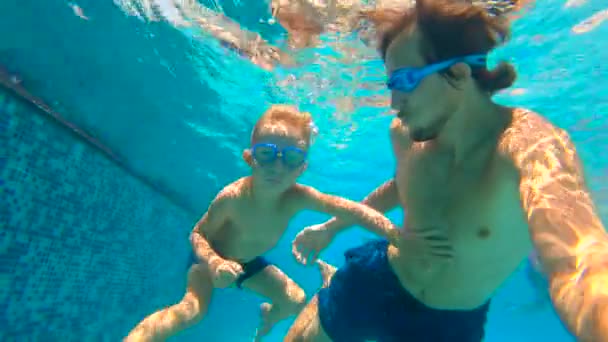 Slowmotion submarino disparo de padre y su hijo pequeño swining buceo y divertirse en una piscina — Vídeo de stock