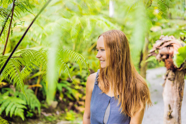 Beauty young woman walks among ferns at daytime