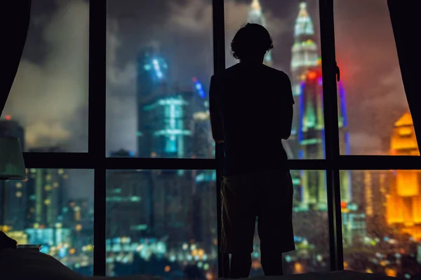 El hombre mira por la ventana a la ciudad nocturna —  Fotos de Stock