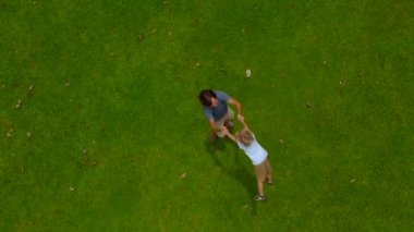 Bir baba oğlu yeşil çim üzerinde onun kollarında çember hava slowmotion vurdu. Kamera yükseltir kadar