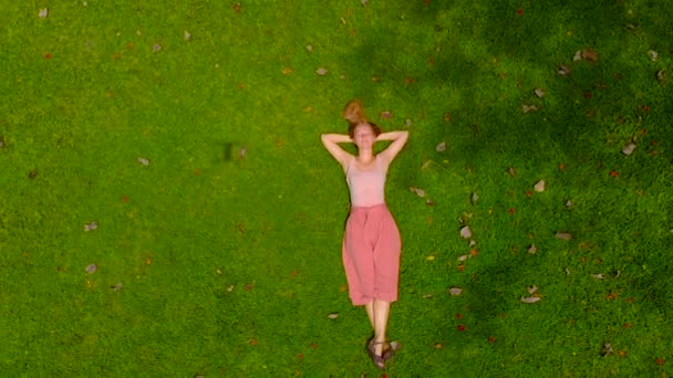 Luchtfoto van tikje shot van een vrouw laing op een groen gazon. camera verhogingen van — Stockvideo