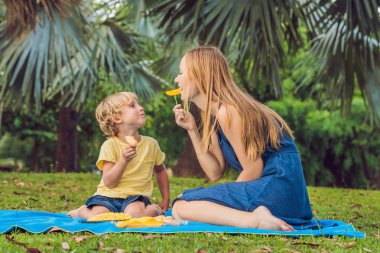 Anne ve oğlu piknik park vardı. Sağlıklı meyve - mango, ananas ve kavun yemek. Çocuk sağlıklı yemek yemek.