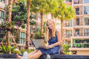 Onun smartphone içinde tarama otelde onu laptop ile havuzun oturan genç kadın serbest meslek sahibi. Bayramlarda meşgul. Uzak iş kavramı. Metniniz için kopya alanı.