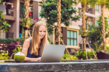 Onun smartphone içinde tarama otelde onu laptop ile havuzun oturan genç kadın serbest meslek sahibi. Bayramlarda meşgul. Uzak iş kavramı. Metniniz için kopya alanı.