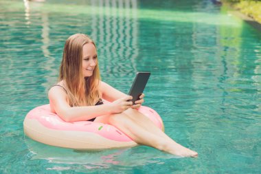 Onun smartphone içinde tarama otelde onu laptop ile havuzun oturan genç kadın serbest meslek sahibi. Bayramlarda meşgul. Uzak iş kavramı. Metniniz için kopya alanı.
