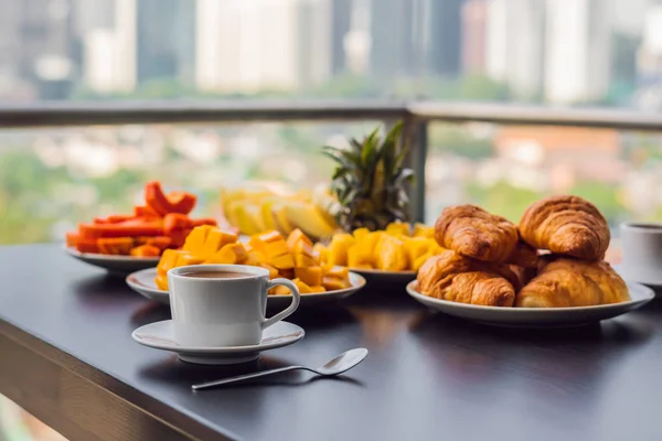 Frühstückstisch mit Kaffeeobst und Brotcroisant auf einem Balkon vor dem Hintergrund der Großstadt — Stockfoto