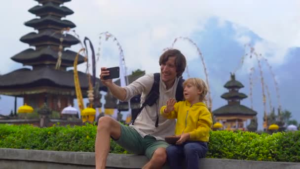 Pai e filho tirando selfie na frente de um templo Pura Ulun Danu no lago Bratan em Bali, Indonésia — Vídeo de Stock