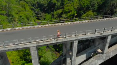 Bir kadın ve oğlu onun alt tropikal içinde bir nehir ile bir Kanyon geçiş uzun bir köprü üzerinde duran hava atış. Anne çocuğa bir şey gösterir.