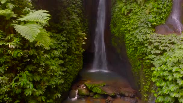 Aerial View of the Leke Leke waterfall in jungles of Bali, Indonesia. Drone moves straight and camera tilts up — Stock Video