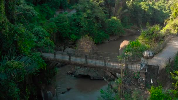 Tiro aéreo de uma pequena ponte sobre o rio com um pequeno templo local sobre ele em Bali, Indonésia. Câmera explode — Vídeo de Stock