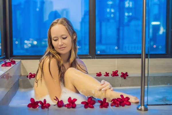 Junge Frau Sitzt Einer Badewanne Mit Schaumstoff Und Frangipani Blumen — Stockfoto