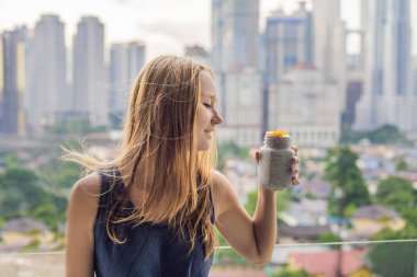 Genç kadın büyük şehir manzaralı onu balkonda Chia puding yemek.